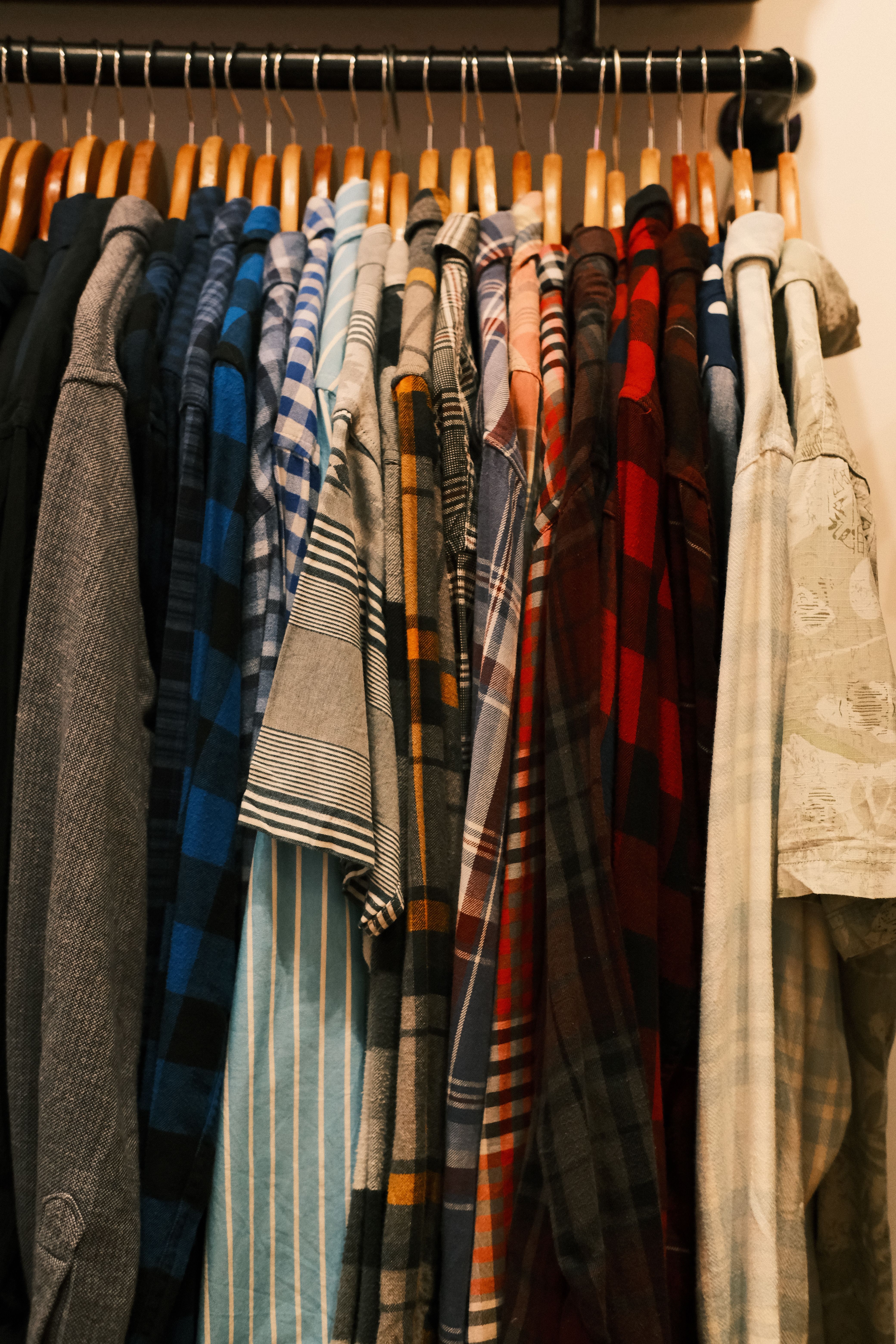 Rack of plaid and striped shirts on wooden hangers