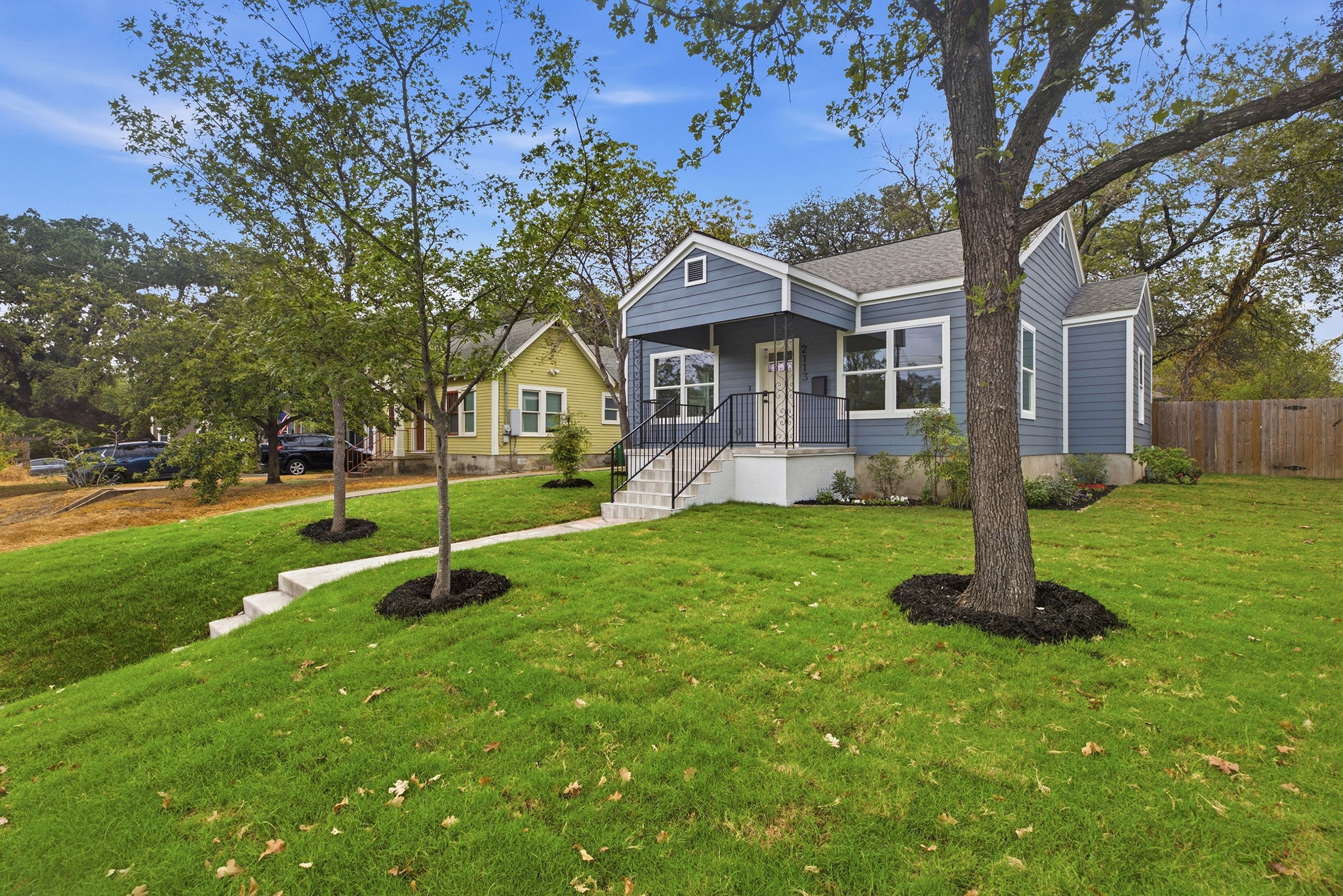 Corner view of the home and front lawn under mature trees