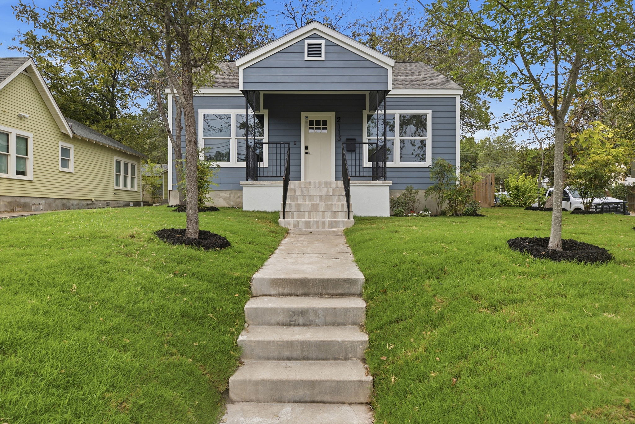 Front of 2113 Wilson St with blue siding, a covered front porch and steps up from the sidewalk