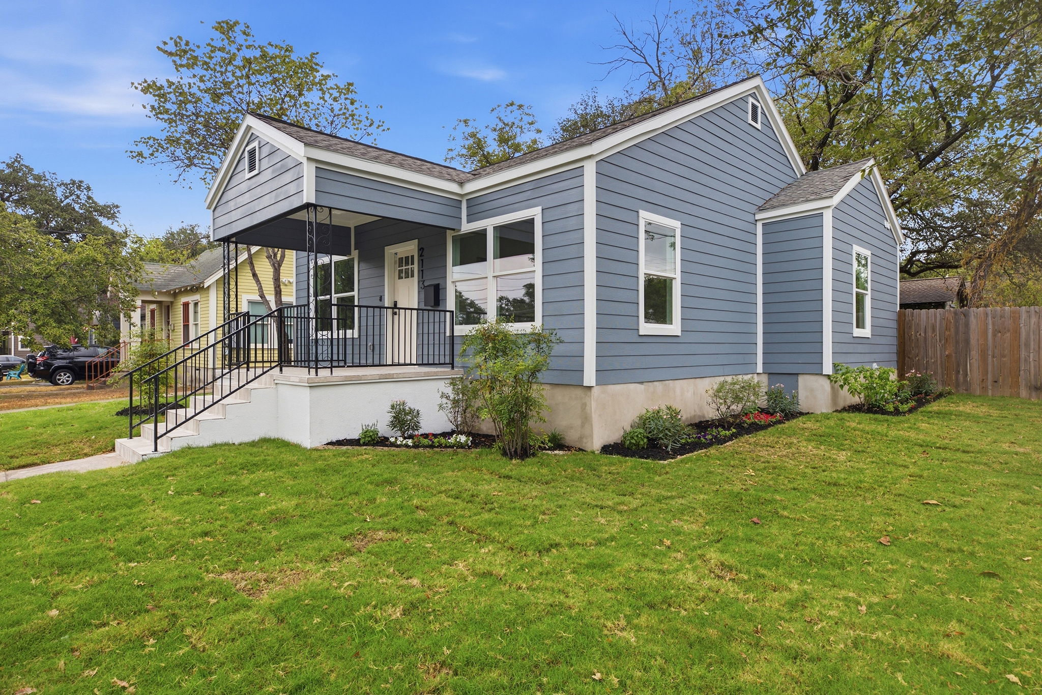 Side view of the home from the corner with the front porch and a wood privacy fence