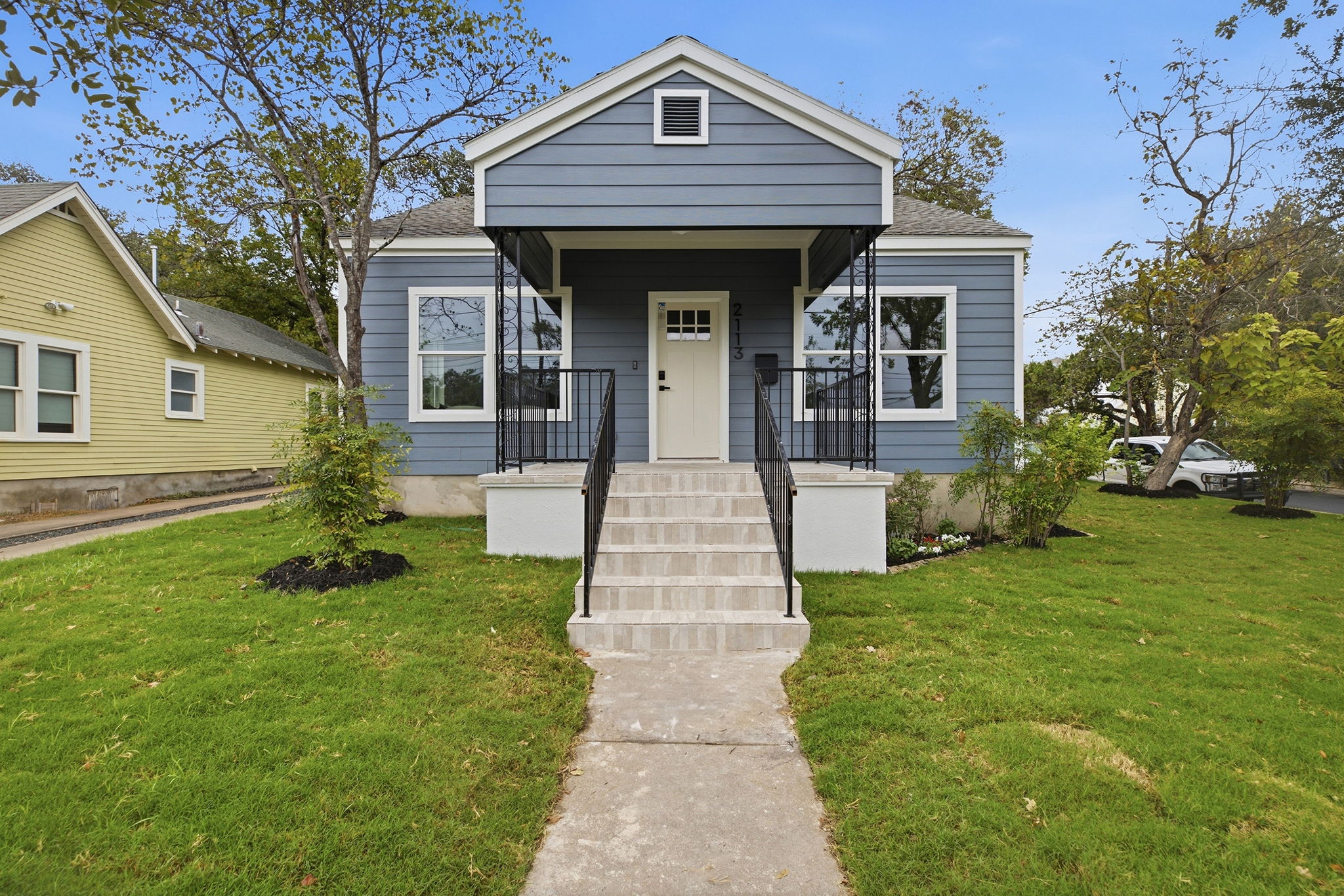 Covered front porch with black railings and front steps