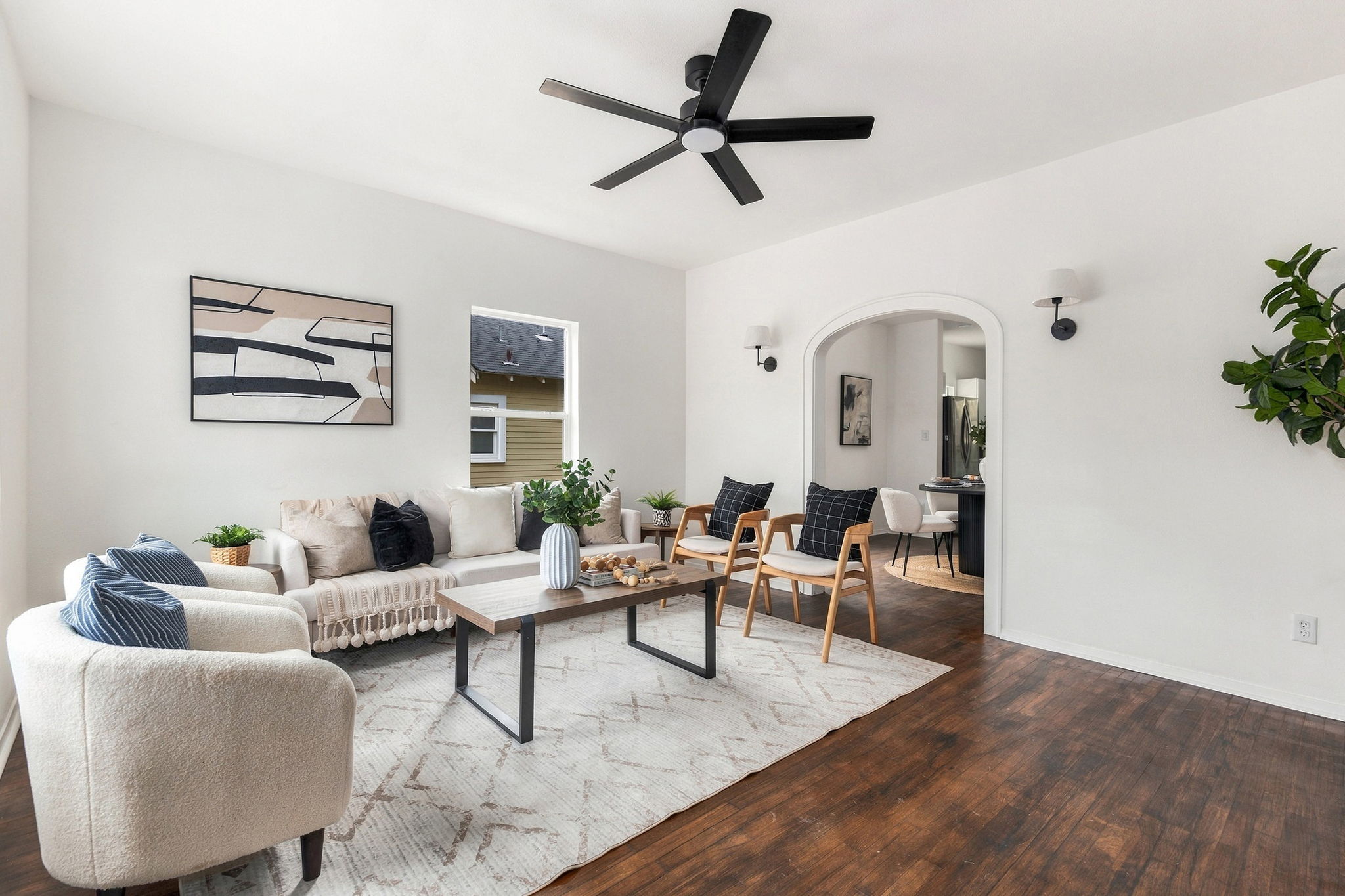 Living room with a ceiling fan and an arched opening to the dining area
