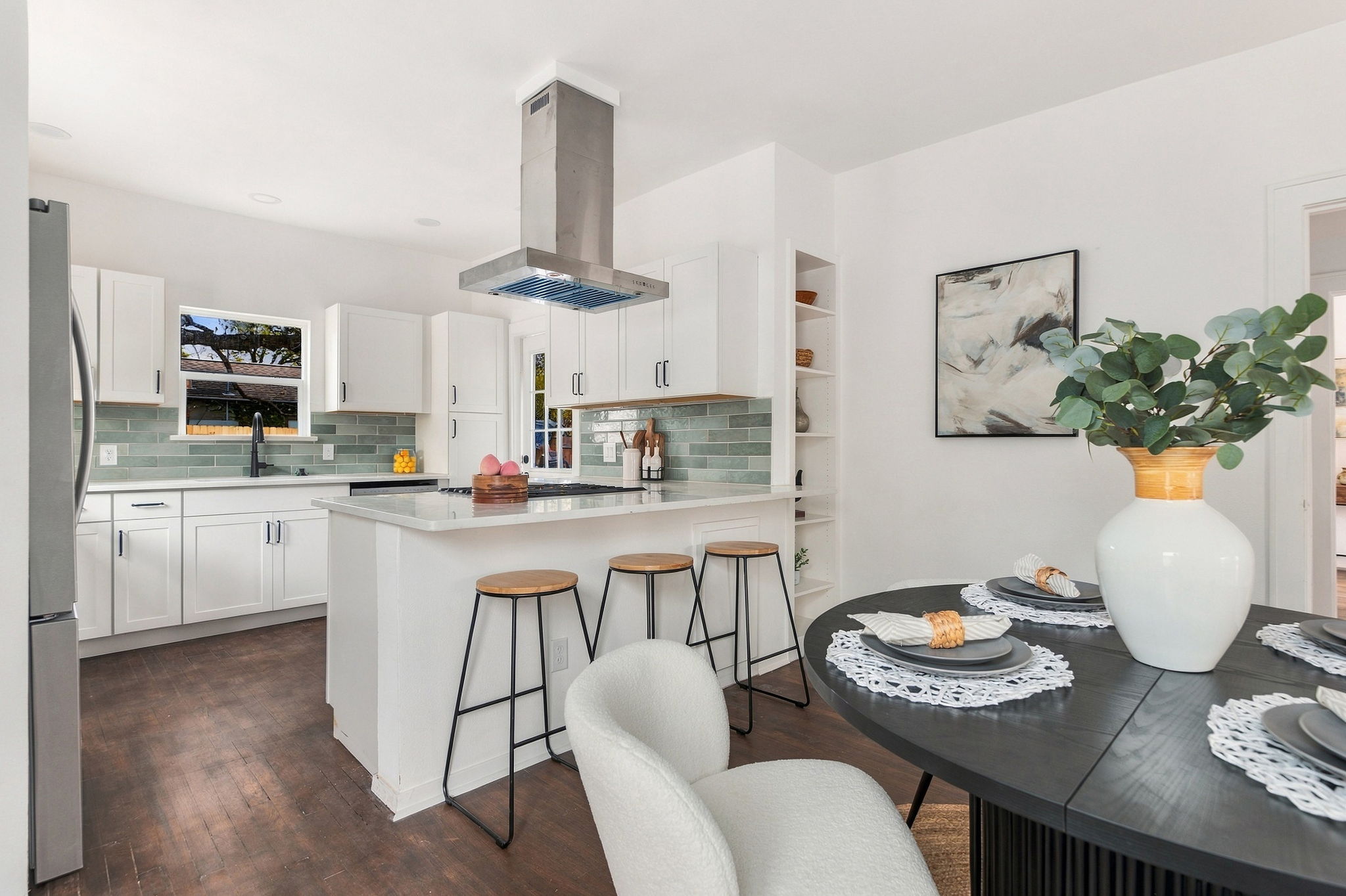 Kitchen with white shaker cabinets, green subway tile and a stainless range hood