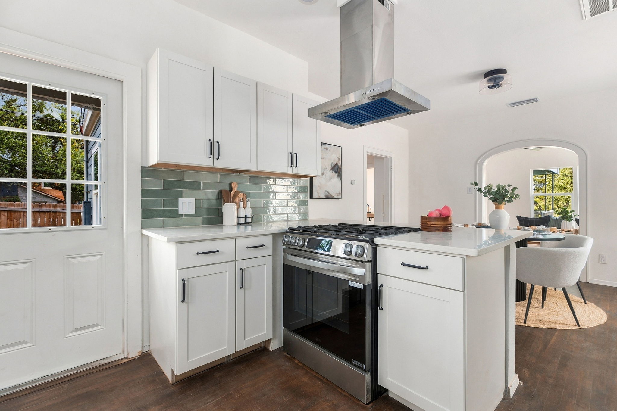 Kitchen gas range and white cabinets with a view through the arch to the dining area