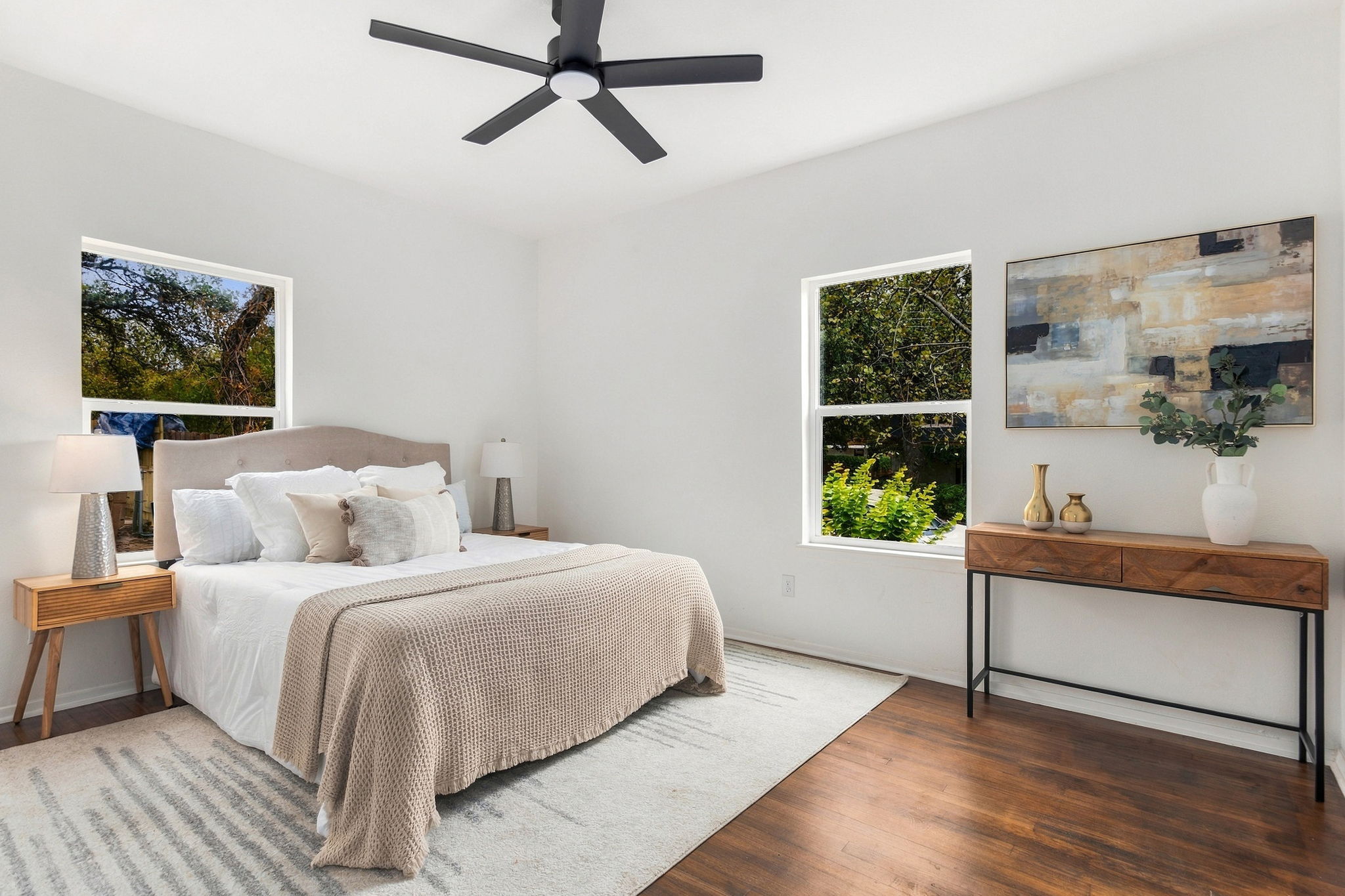 Primary bedroom with a ceiling fan and windows on two walls