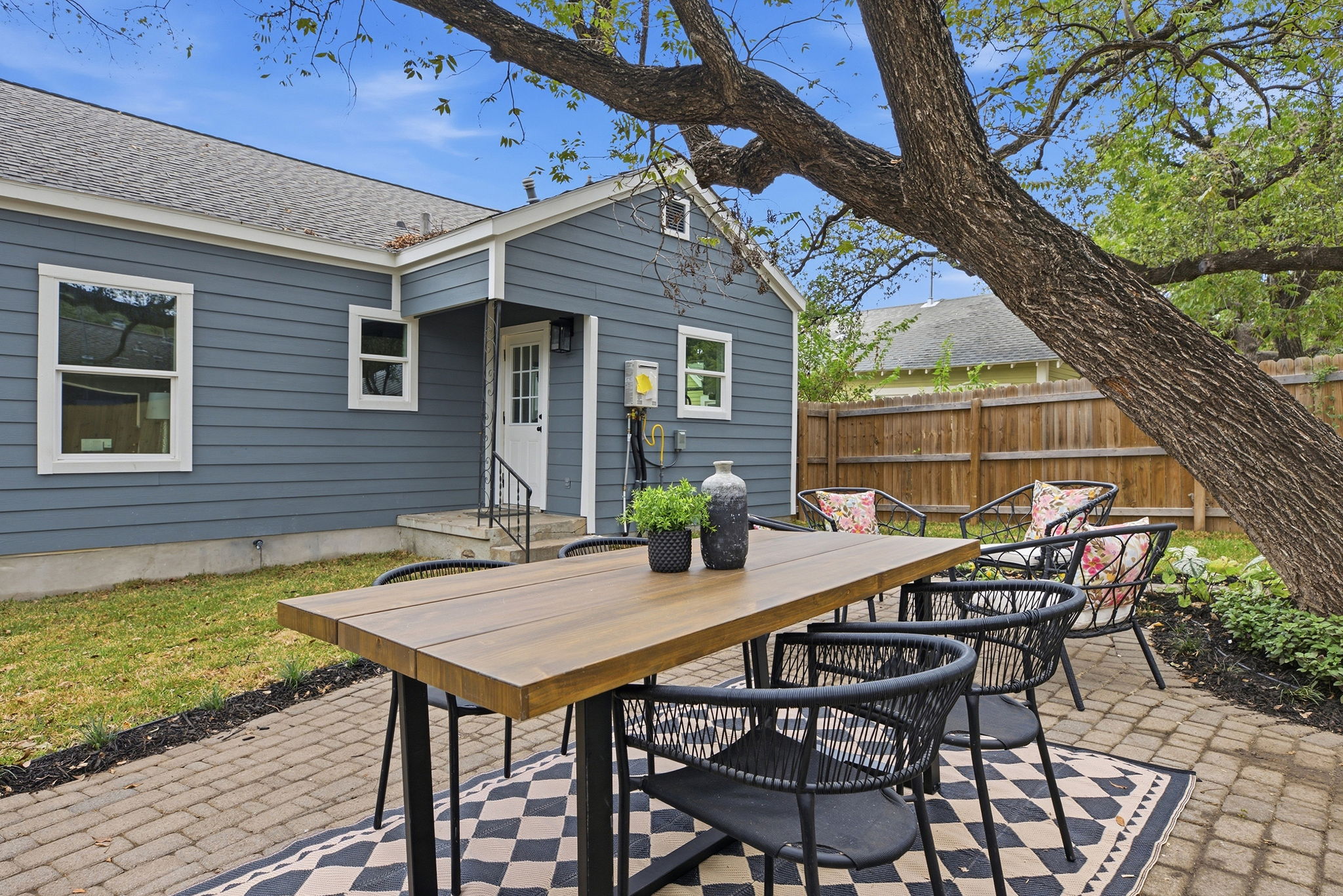 Brick paver patio with outdoor dining under a mature shade tree