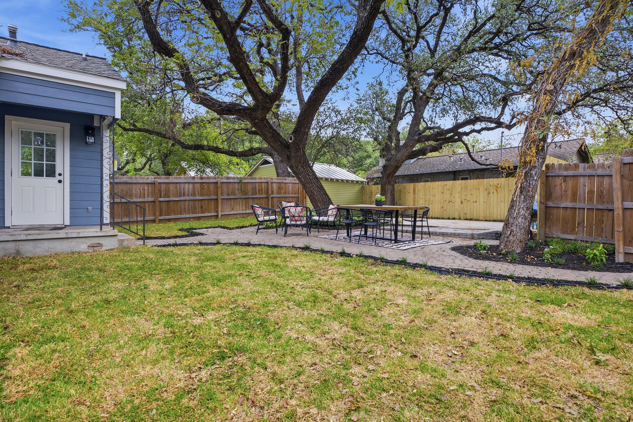 Fenced backyard with lawn, paver patio and mature trees