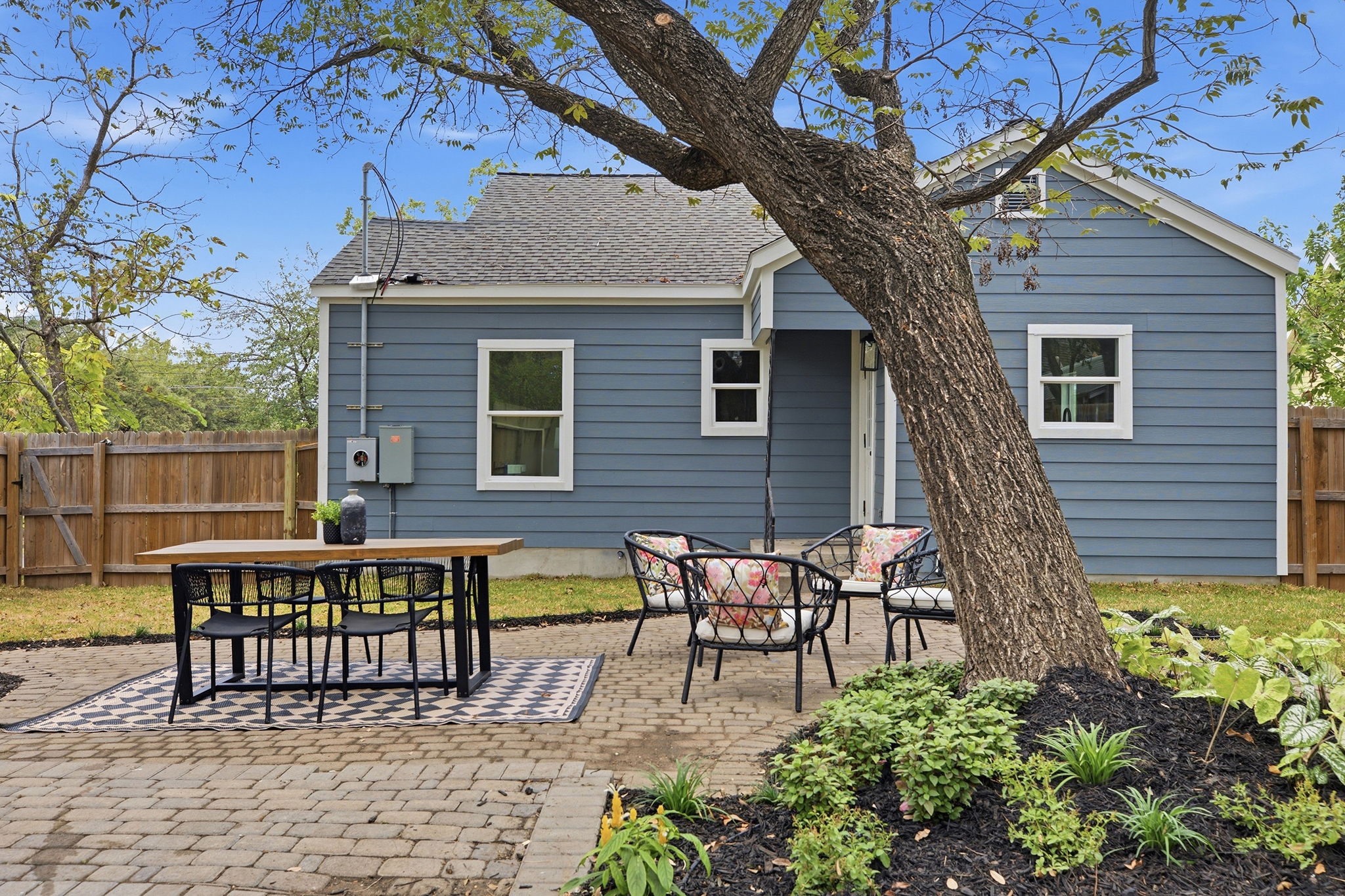 Rear of the home with patio seating under a large shade tree