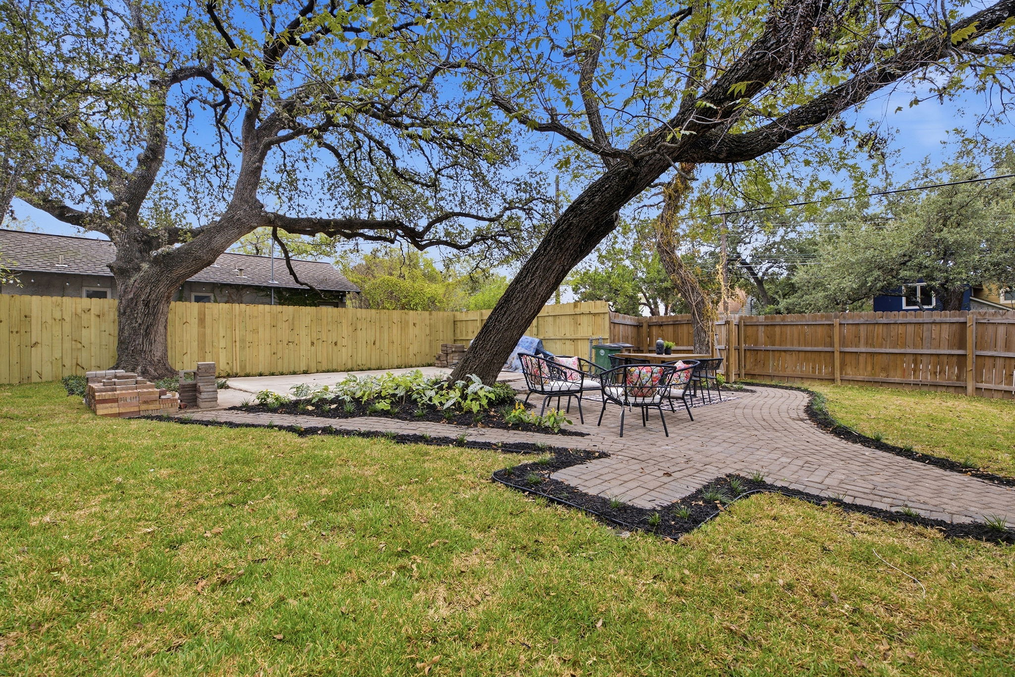 Backyard with a curving paver path, lawn and two large shade trees