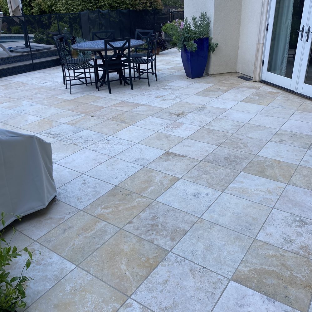 Clean travertine patio with dining table and French doors after professional restoration in San Jose