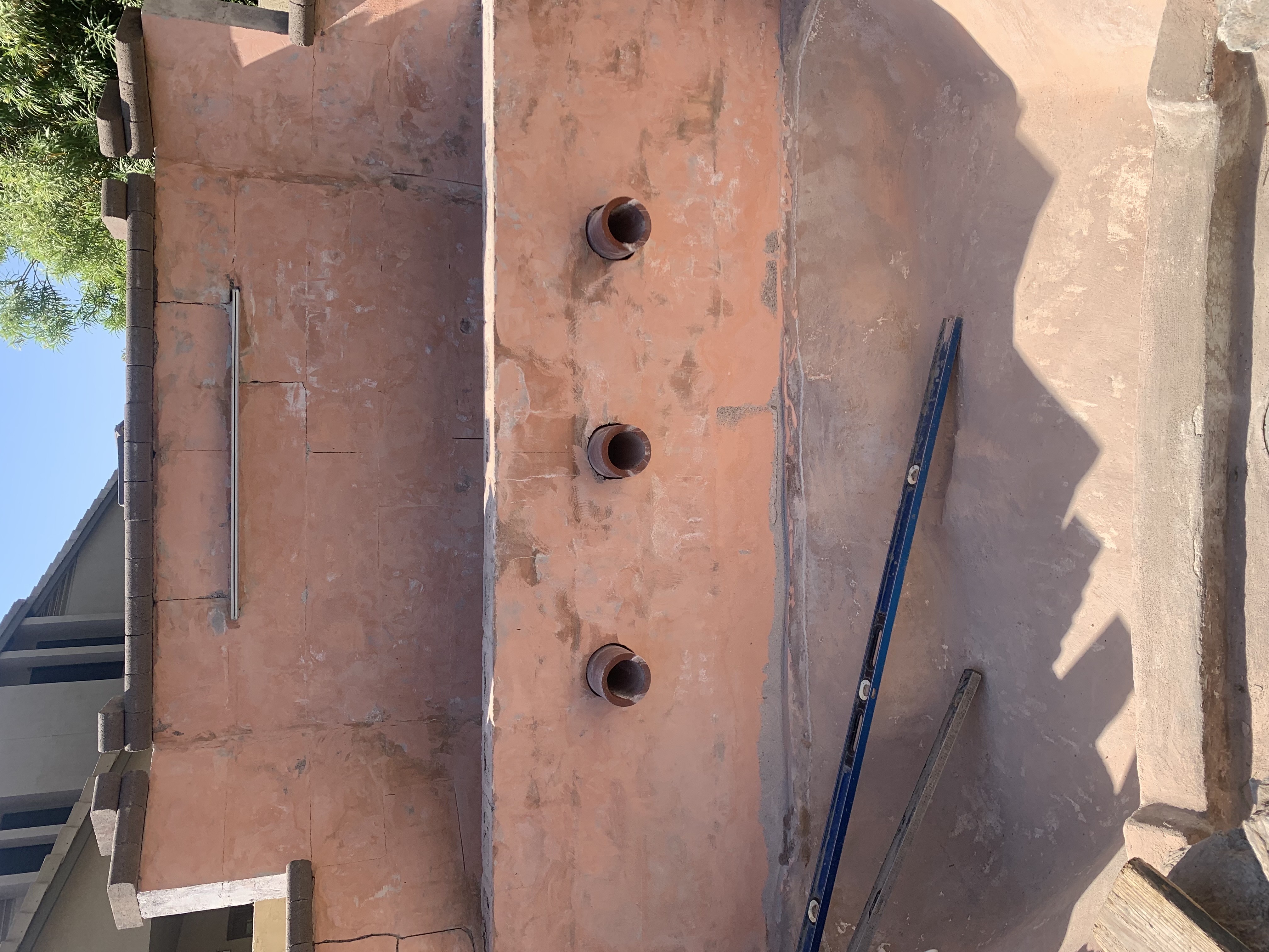 Before — raw concrete wall with pipe holes drilled