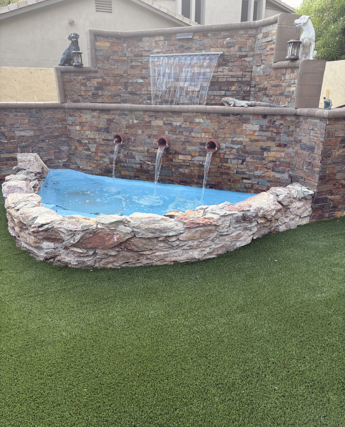 After — finished natural stone water wall with spouts and grass surround