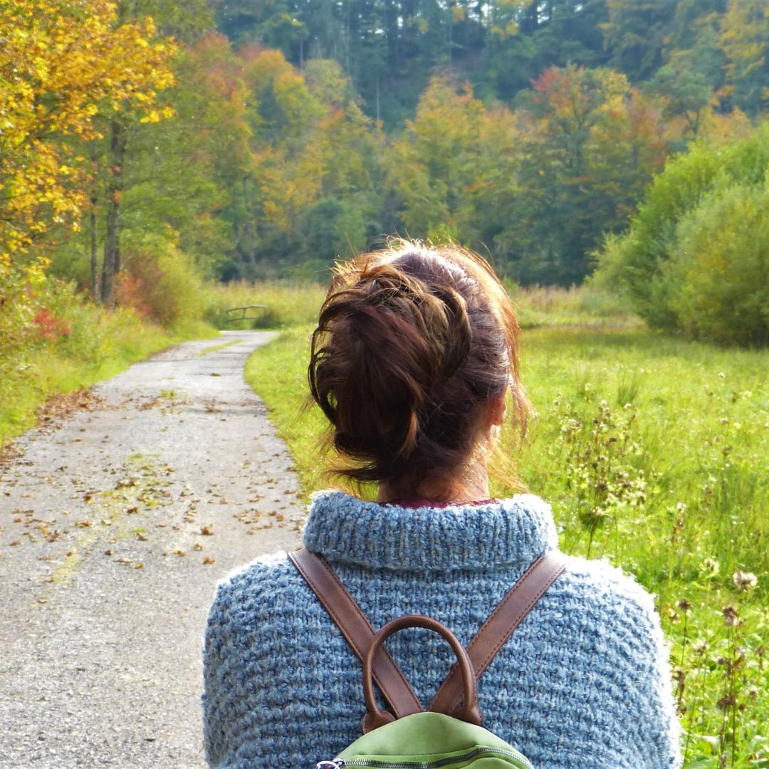 A woman walking down a path into the forest, symbolizing a journey out of anxiety