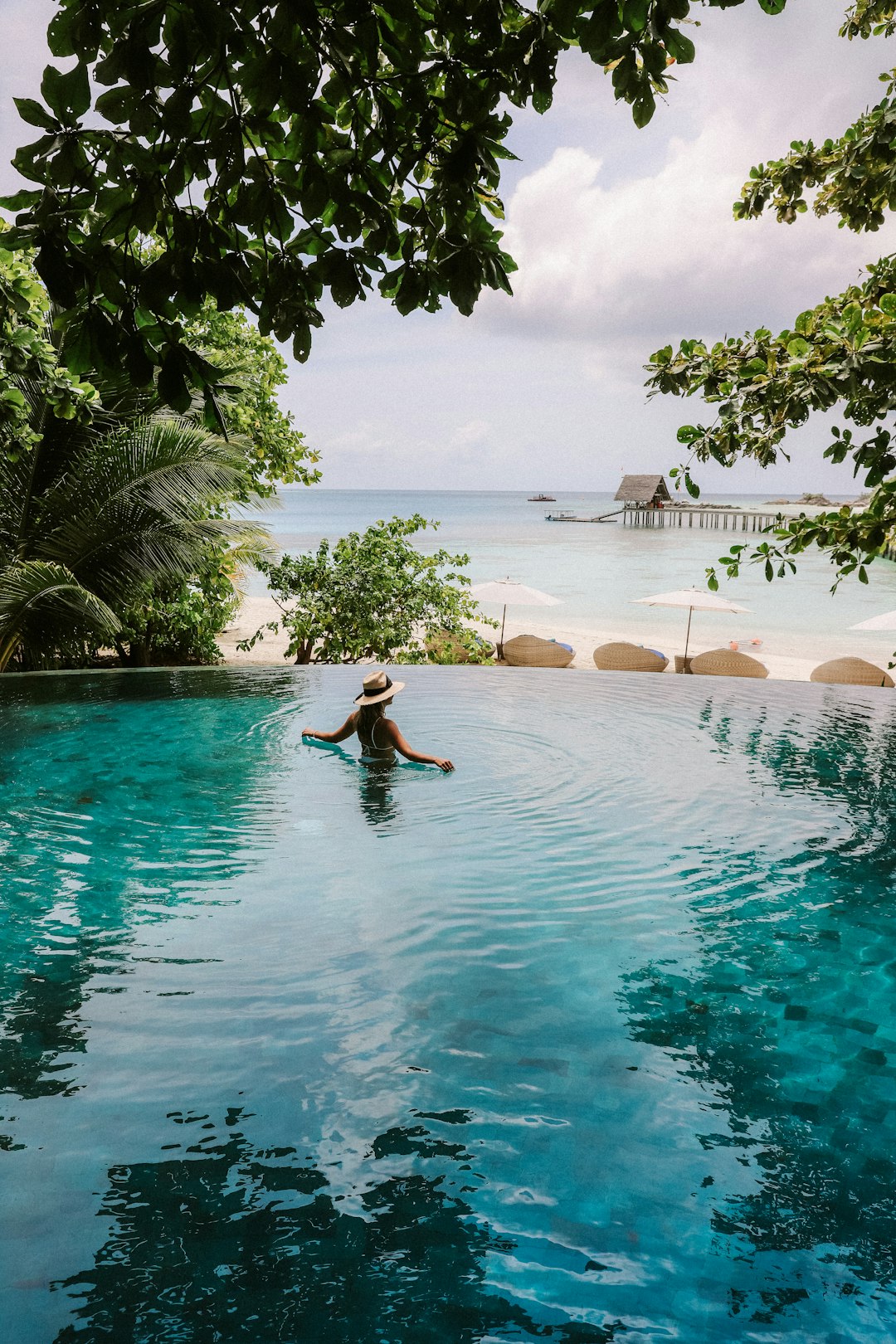 Female Standing in Infinity Pool Looking at the Beach