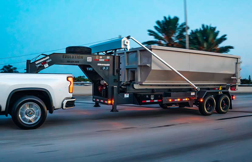 Original gray Evolution roll-off trailer with container being towed