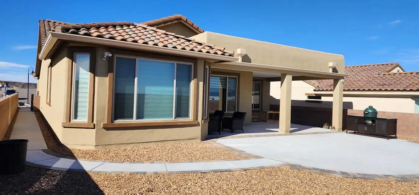 Stucco home with a covered patio and a gutter along the roofline