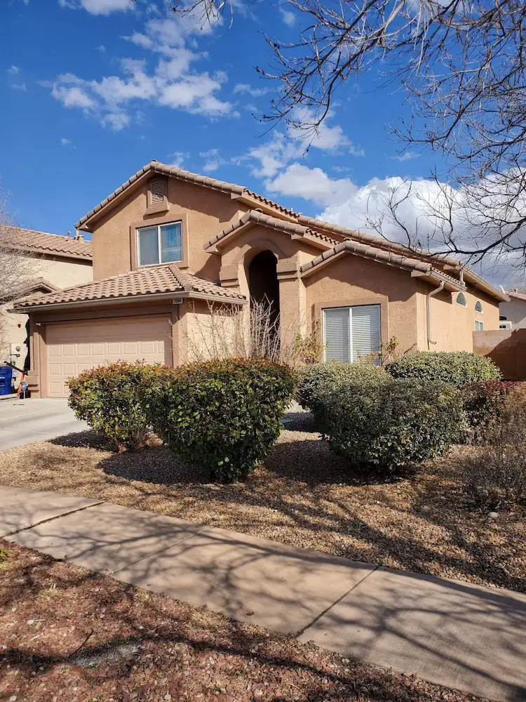 Two-story stucco home with a tile roof and gutters