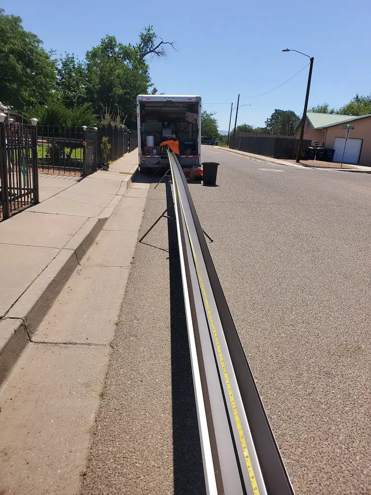 Long continuous gutter section laid out on a driveway before installation