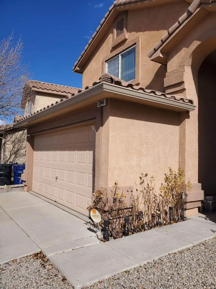 Tan stucco home and garage with a gutter along the roof edge