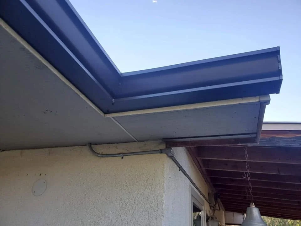 Corner of a gutter and fascia seen from below against a clear sky