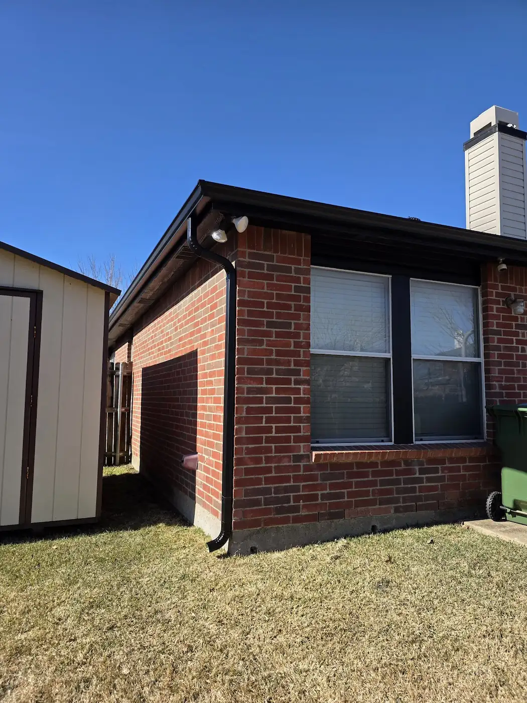Brick home with tall windows and a gutter run along the eave