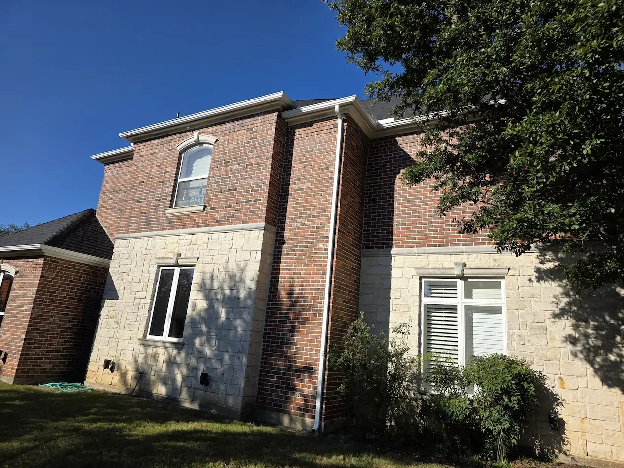Two-story brick home with gutters and downspouts on the side elevation