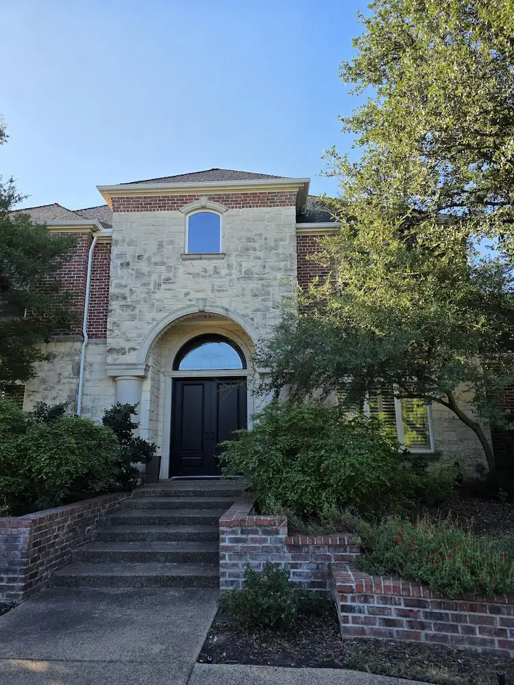 Stone home with an arched entry and gutters along the upper roofline