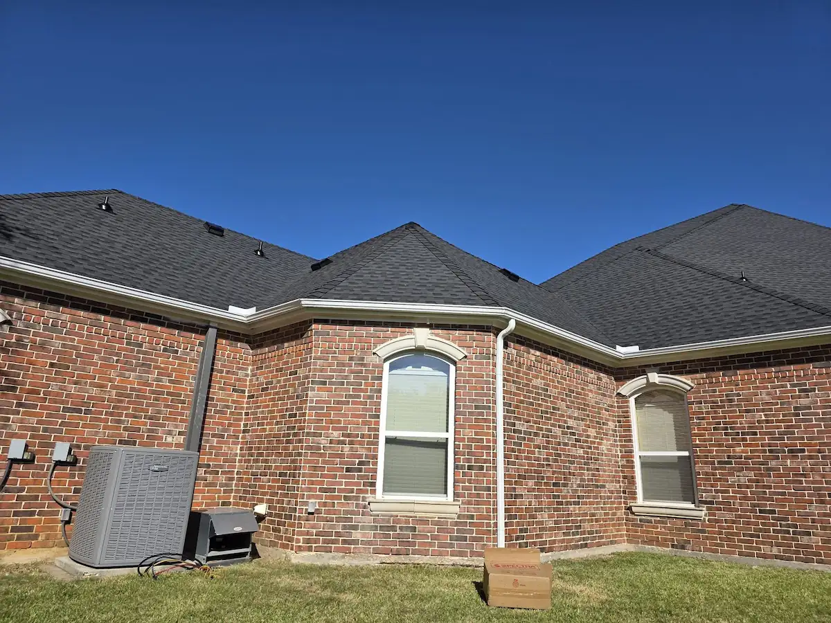 Brick home with a multi-gable shingle roof and a continuous gutter