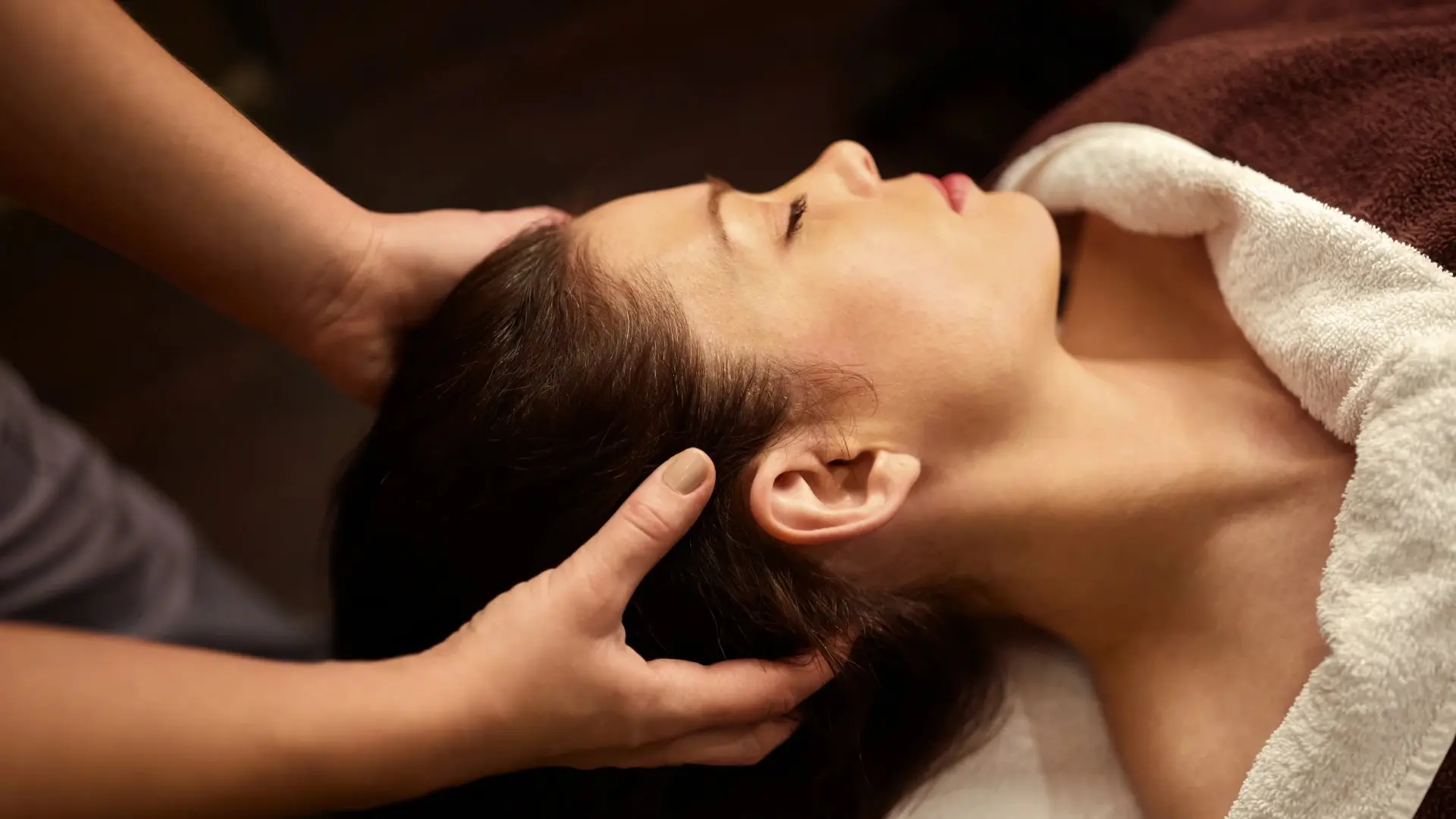 A technician massaging a guest's head in a head spa service