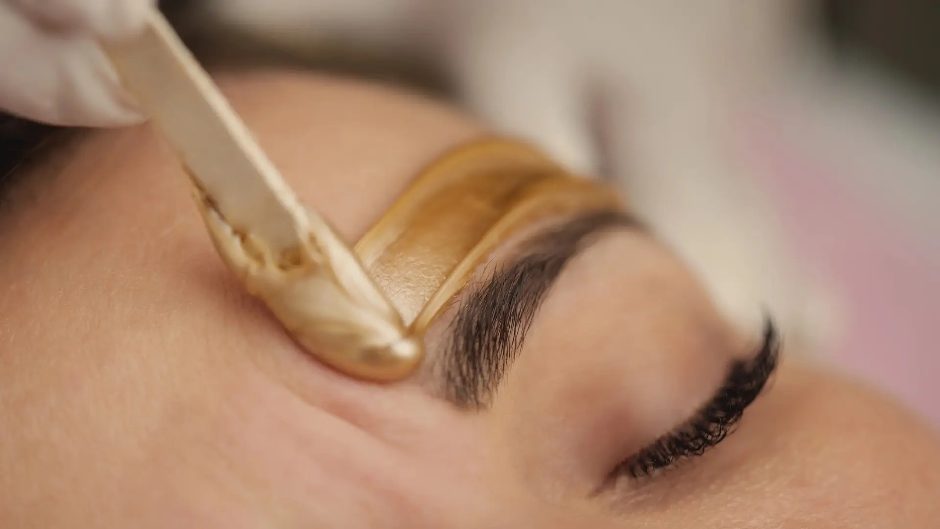 A technician working on waxing a guest's eyebrow