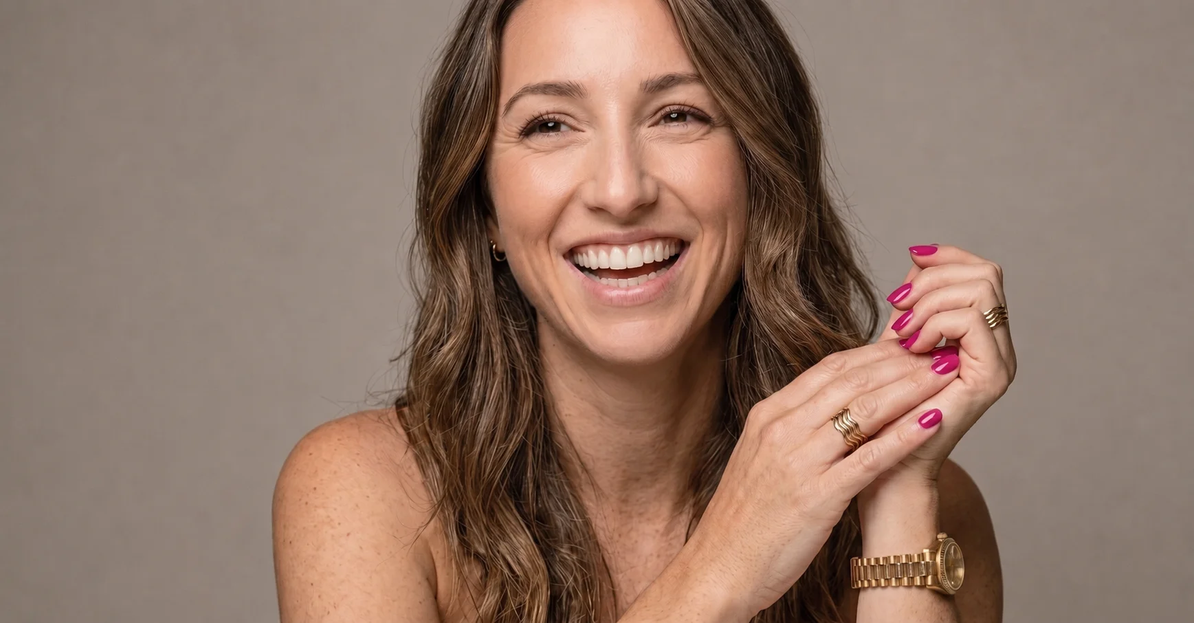 A woman smiling and showing her beautiful pink nails