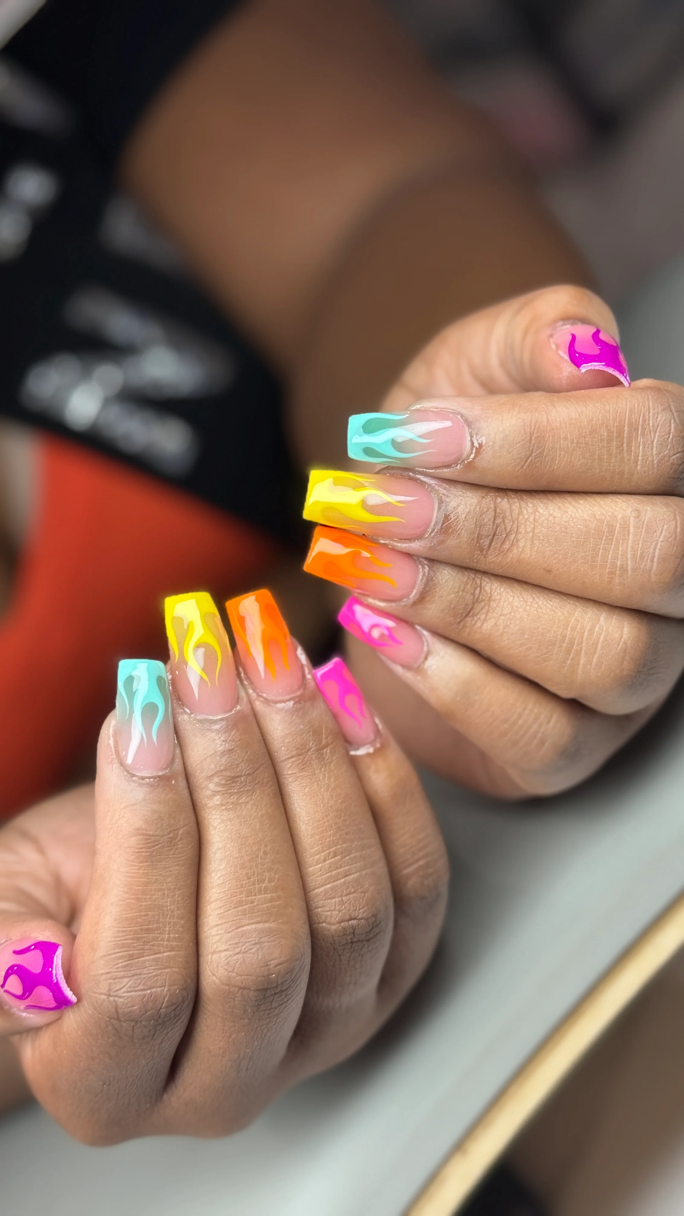 neon flame French nail design with yellow, orange, blue, and pink tips by Ballerina Nails and Spa