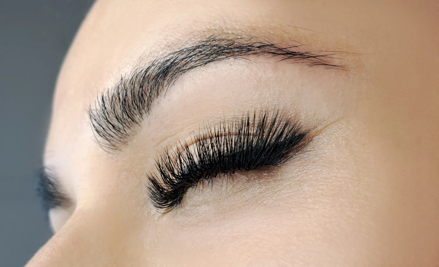 A technician refreshing volume lash extensions during a refill