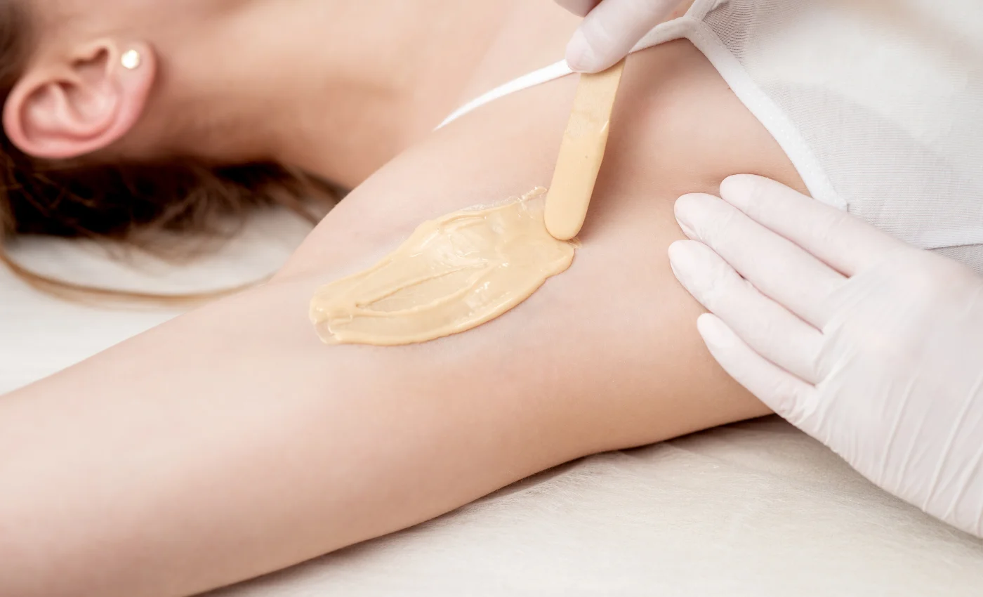 A technician performing an underarm waxing service