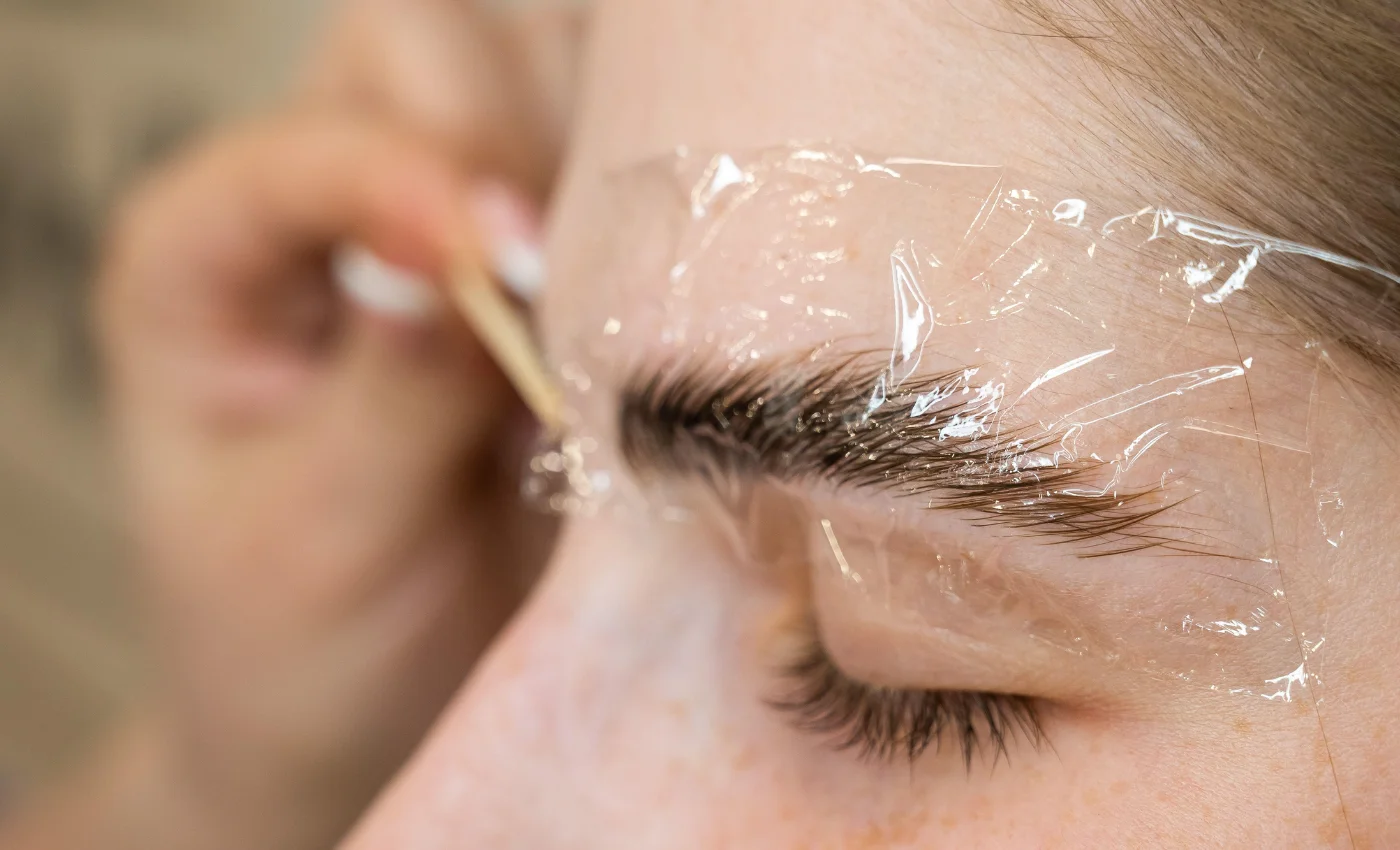 A technician styling brows during a brow lamination service