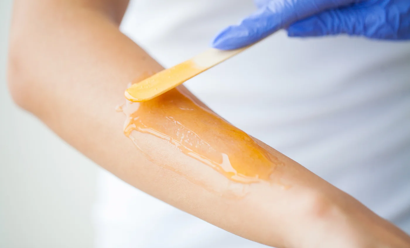 A technician performing a half arm waxing service