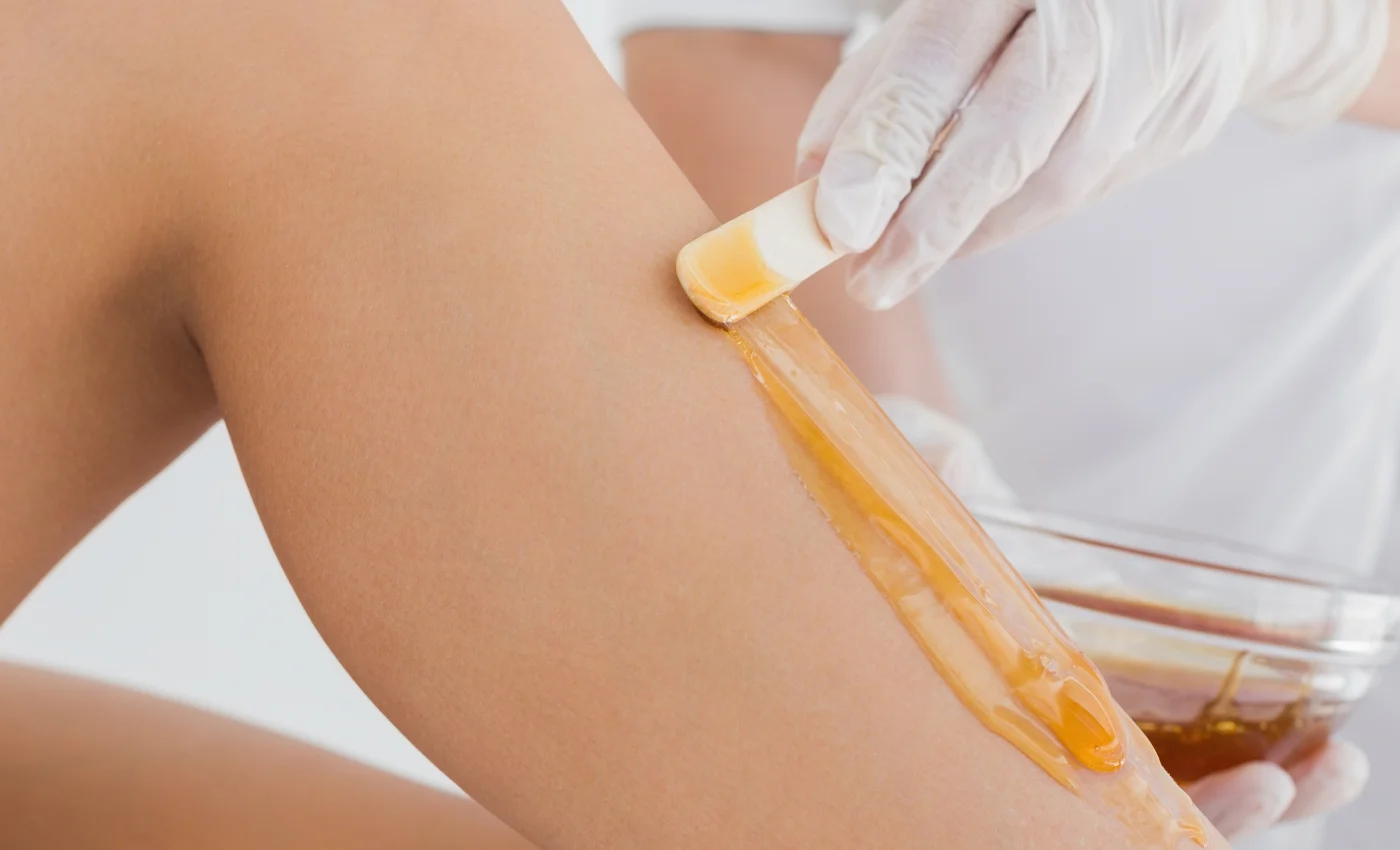 A technician performing a full leg waxing service