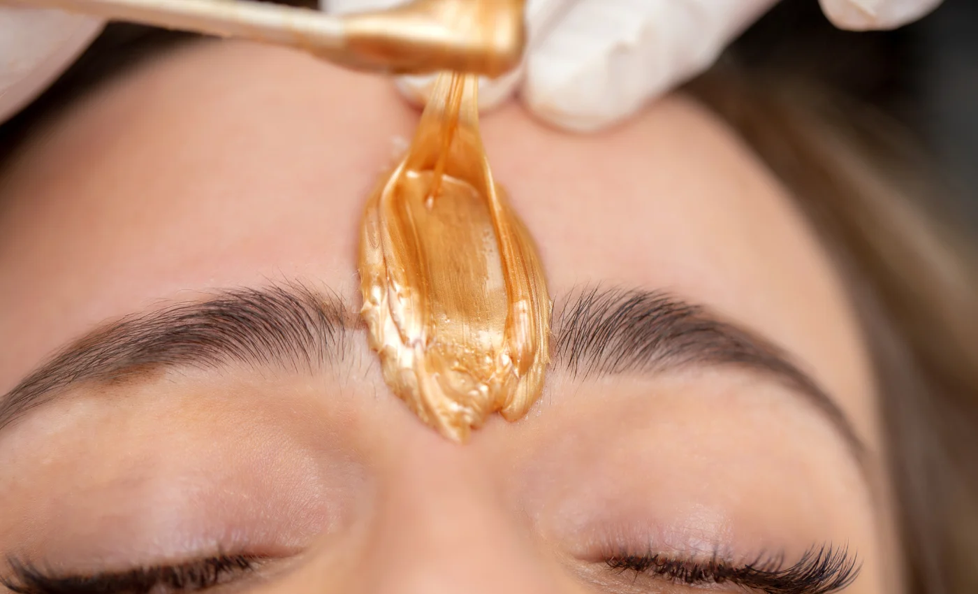 A technician shaping a client's brows during a brow wax service