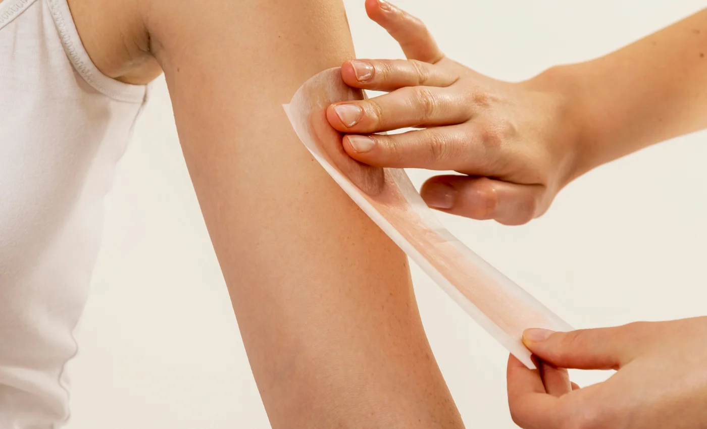 A technician performing a full arm waxing service