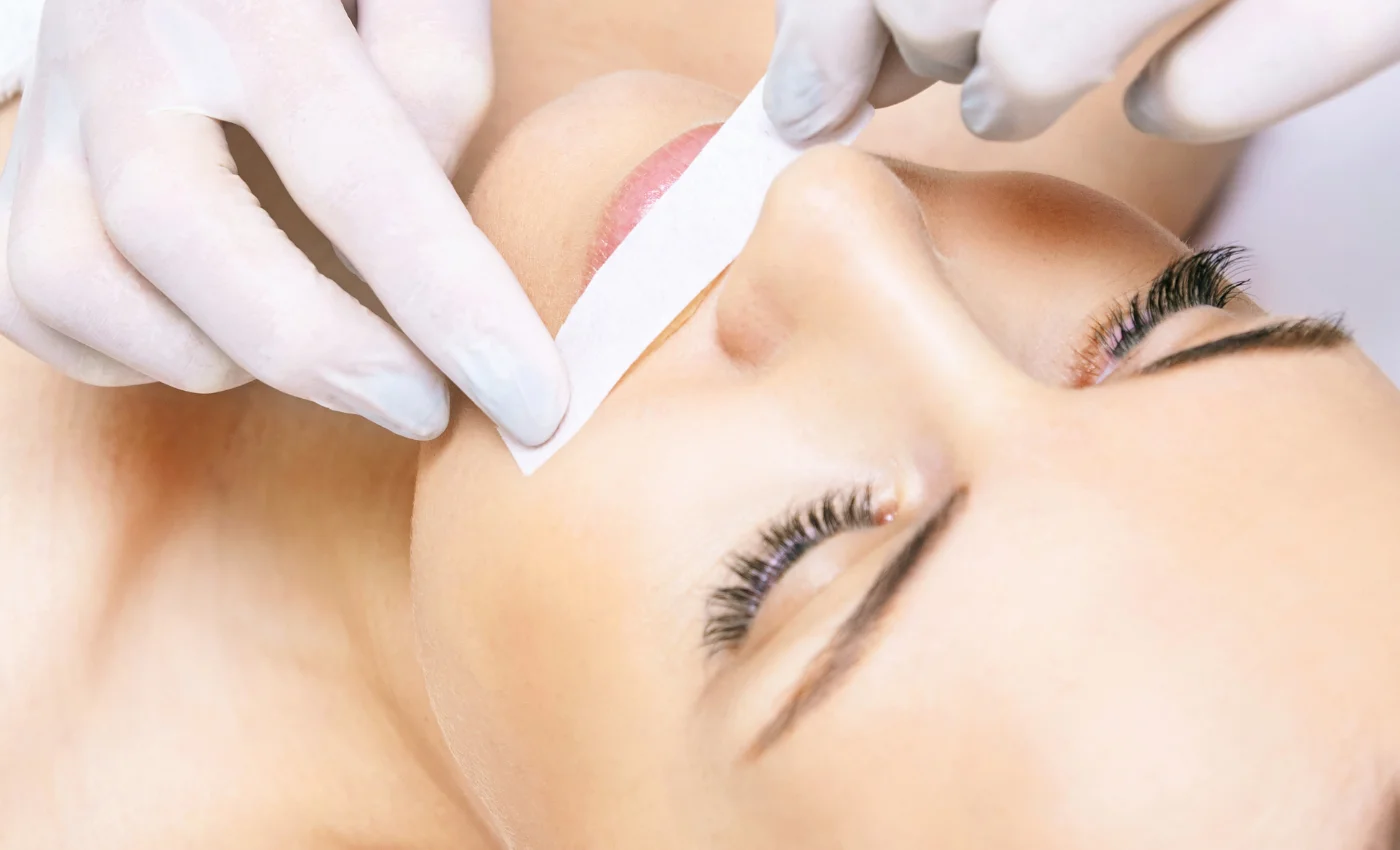 A technician performing a lip waxing service
