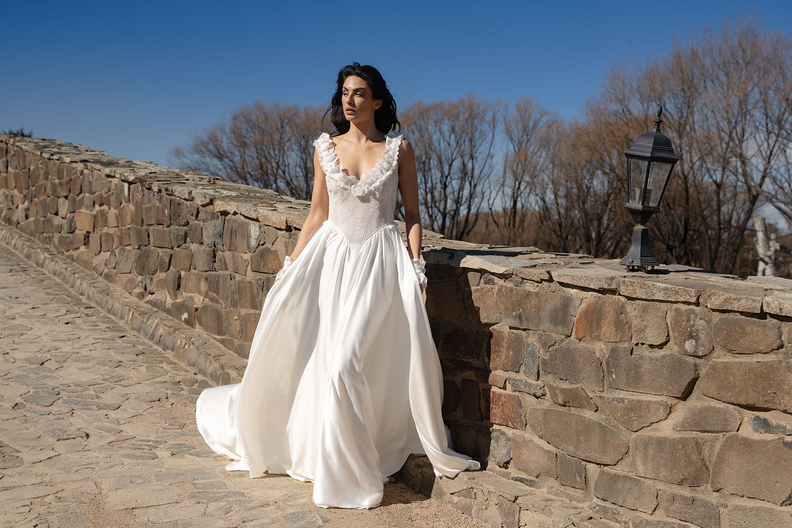 The Vesper, a lace basque gown on a sandstone path