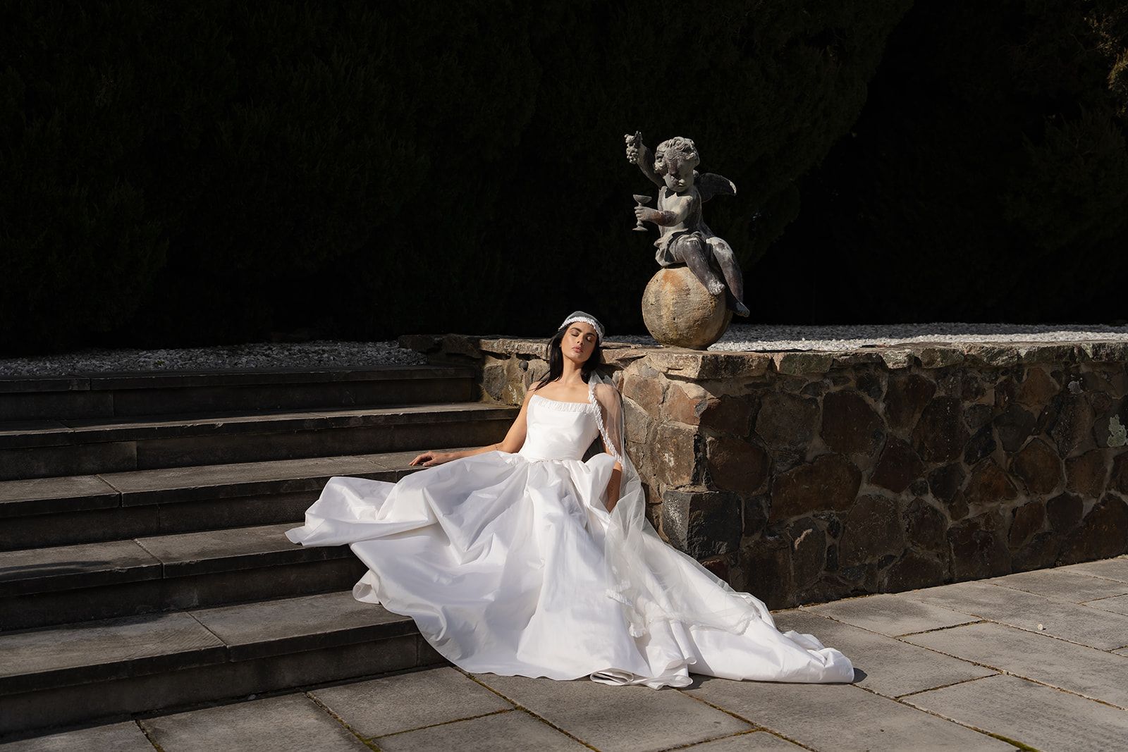 A bride in a strapless taffeta Moira Hughes gown on sandstone steps