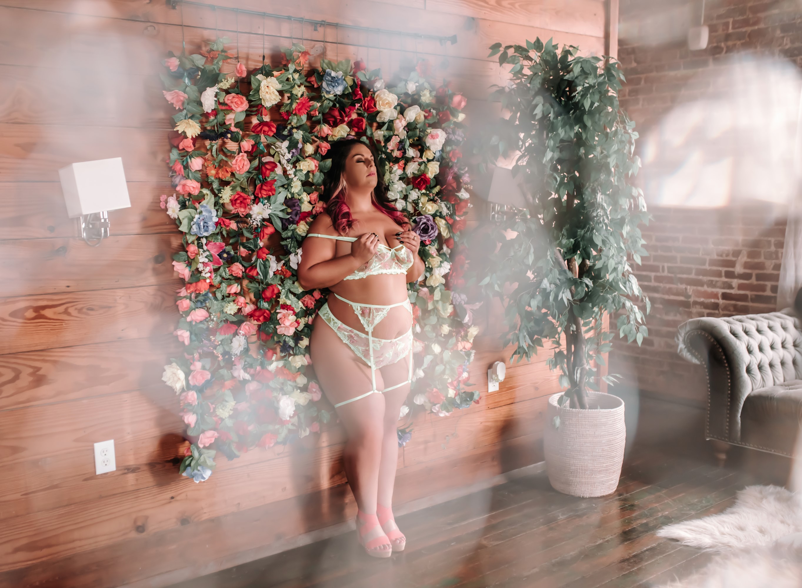 woman in green lingerie standing against flower wall