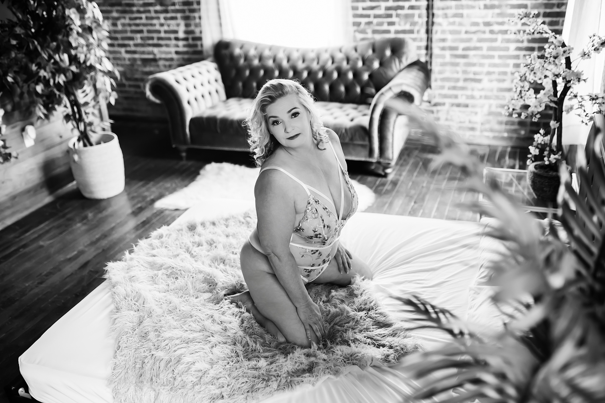 black and white photo of woman in lingerie, kneeling on fur rug