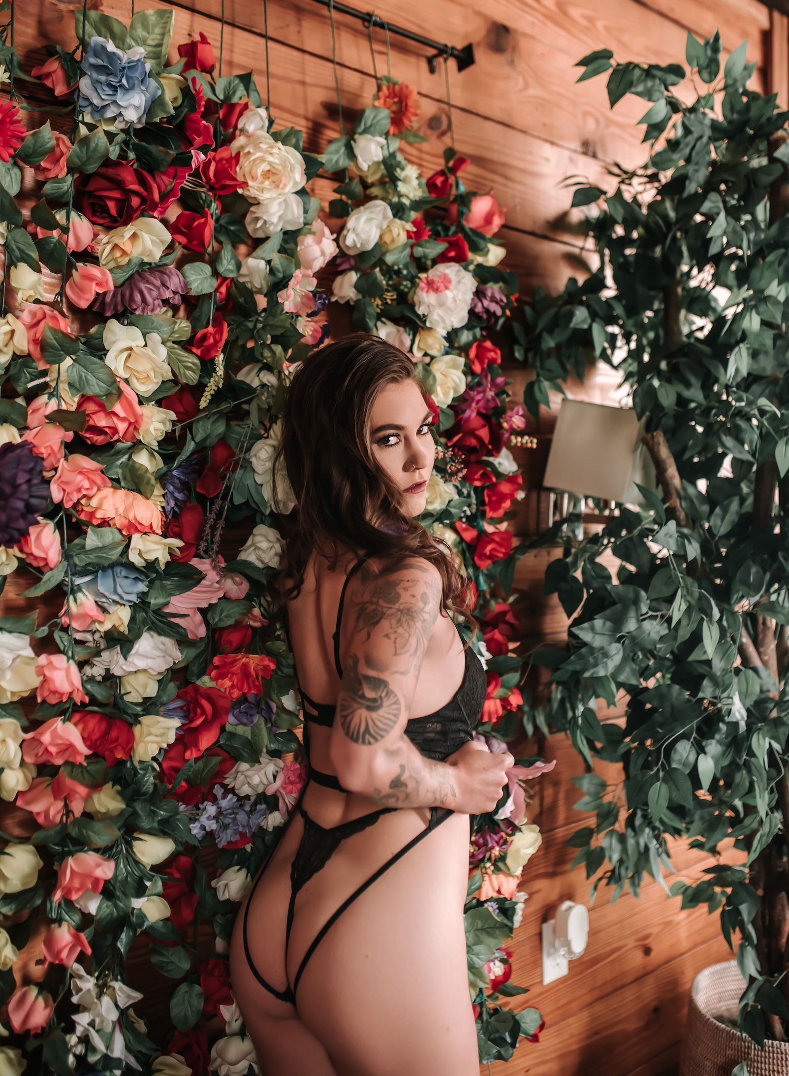 woman wearing black lingerie standing in front of floral wall
