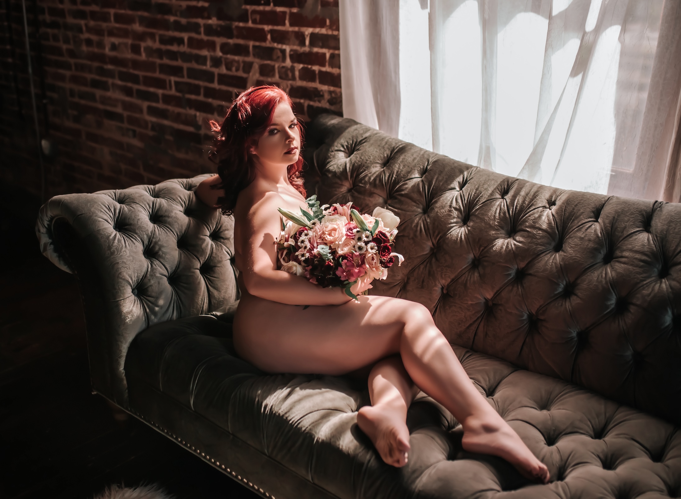 photo of red-haired woman holding a bouquet while lounging on couch