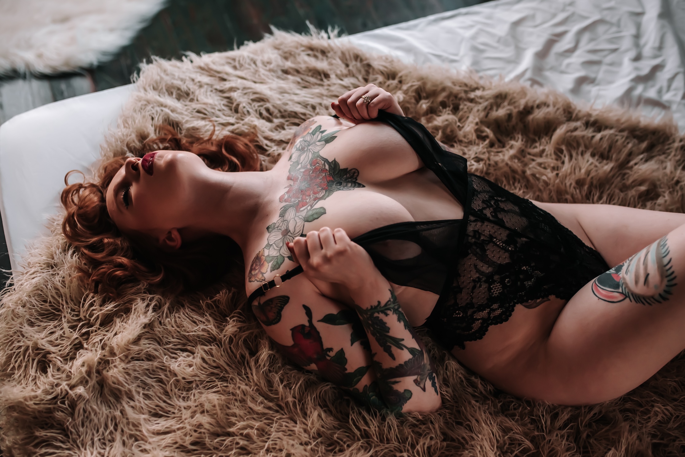 woman laying back on fur rug while wearing black lingerie