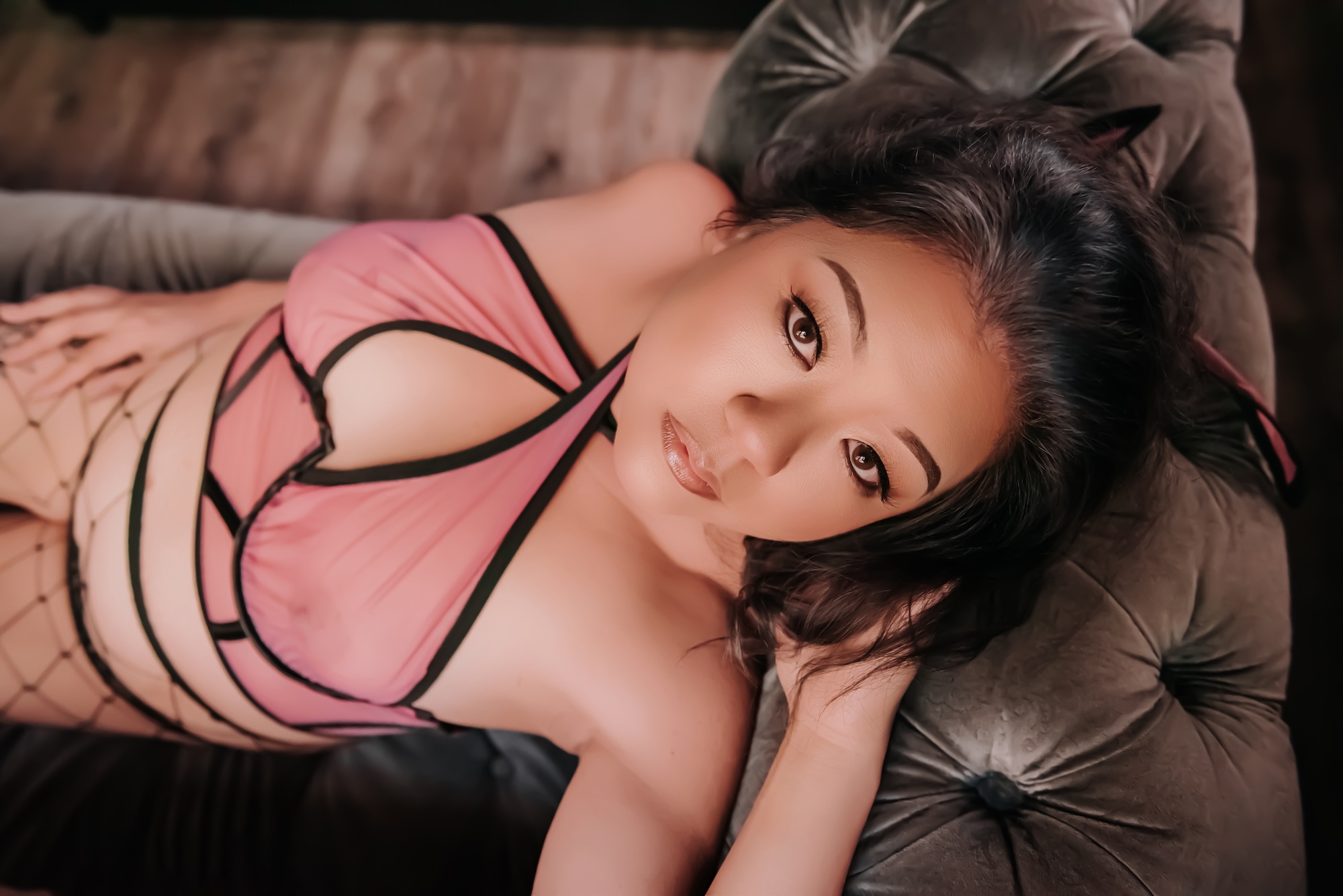 brunette woman wearing white lingerie and lounging on grey couch