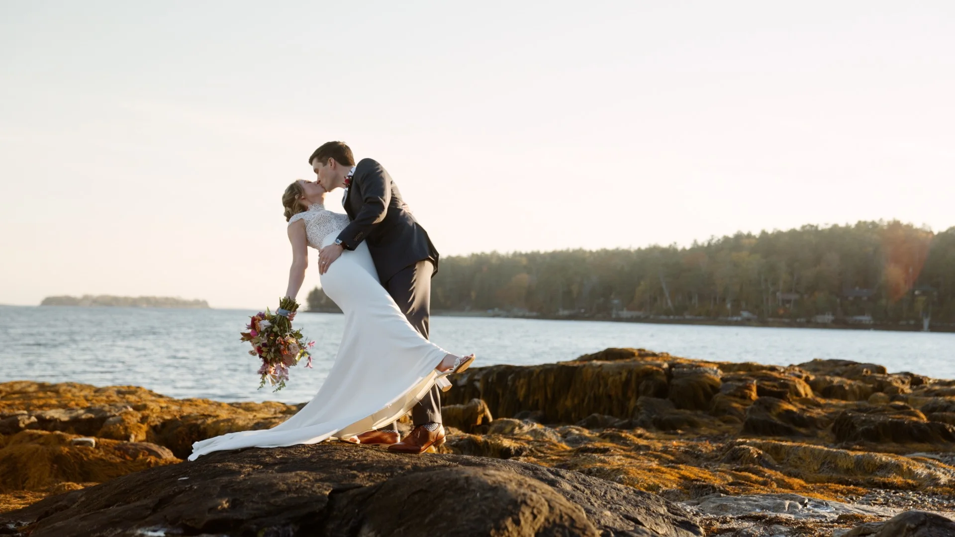 Newlyweds sharing a kiss on the rocky coast, from BHP's wedding portfolio