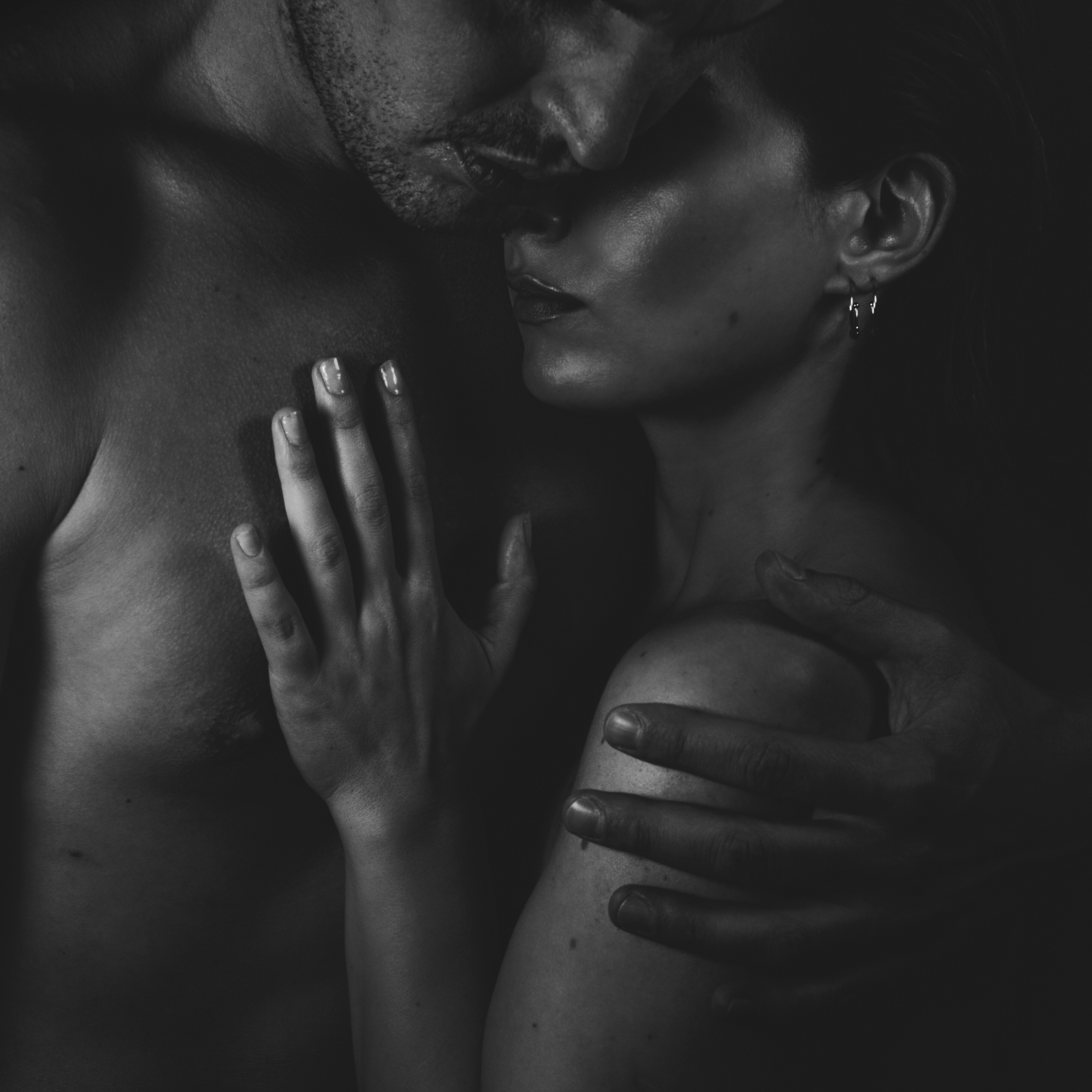 Close embrace of man and woman in shadow, symbolizing eros integration, union of desire and spirit, and holistic leadership with Adam Feuerstein